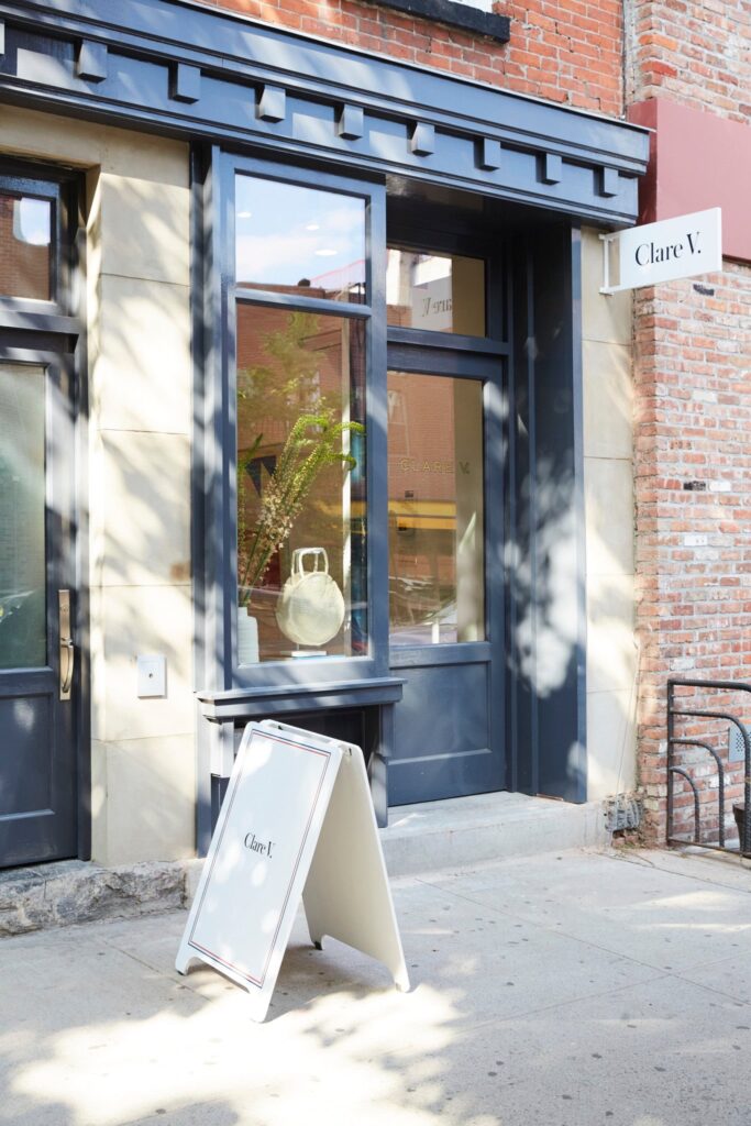 The outside of Clare V fashion shop in Boerum Hill with a blue outside and sign sitting in front of the building.