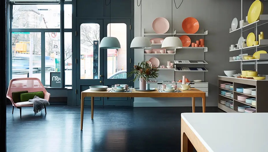 An inside of Mud design shop in Boerum Hill with shelves of colored plates and a table set up in the center of the room.