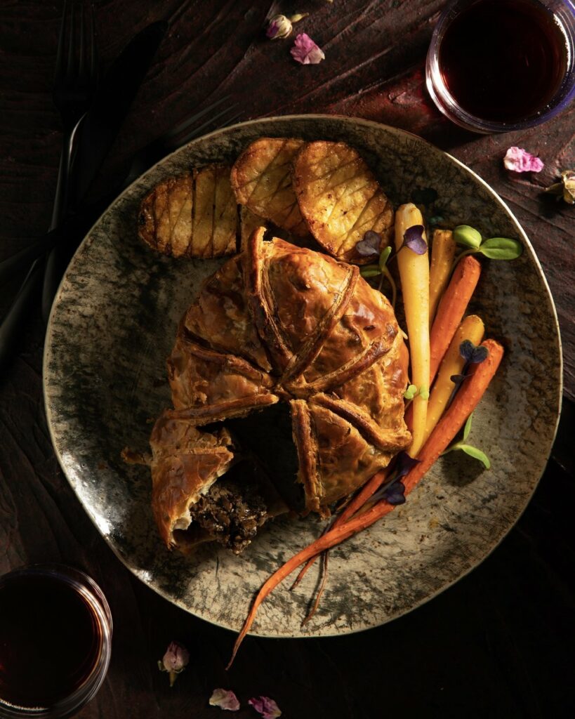 A cut beef wellington and carrots inside a large pot.