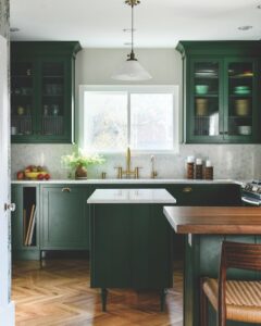 Green cabinets adorn this kitchen redesign alongside wooden floors.