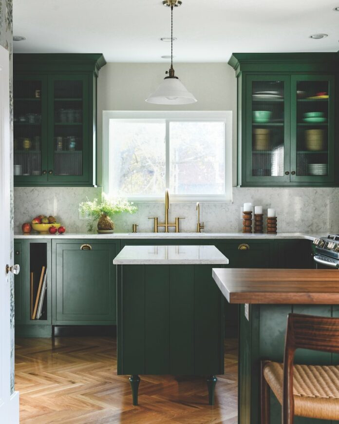 Green cabinets adorn this kitchen redesign alongside wooden floors.