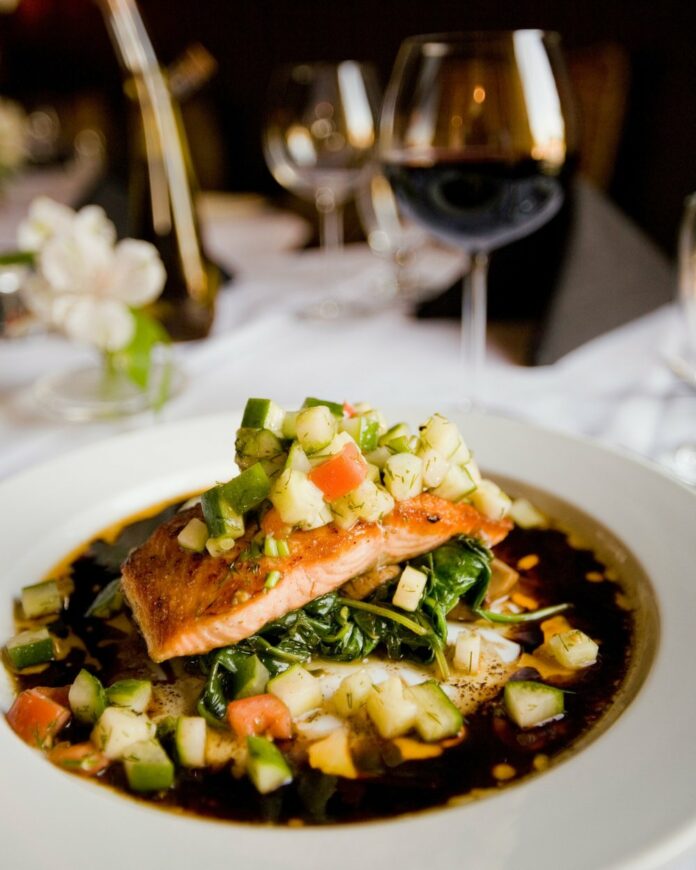 A roasted salmon sits on a bed of spinach, zucchini, and dill relish.
