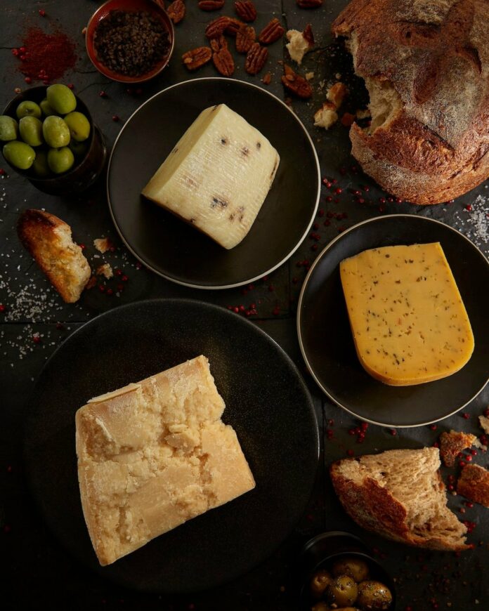 three different blocks of cheese sit in three separate bowls.