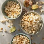 Three bowls of chili-lime popcorn sit on a white table.