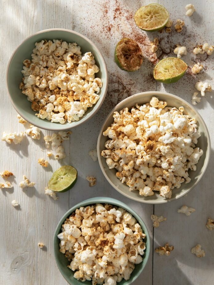 Three bowls of chili-lime popcorn sit on a white table.