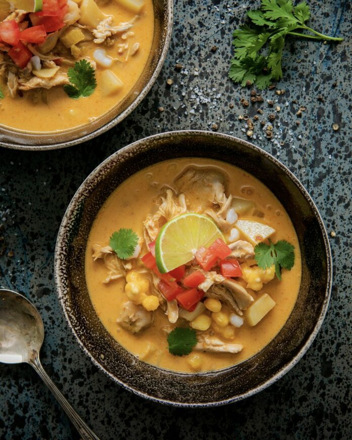 Chipotle chicken chowder on a black background, garnished with lime.