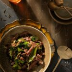 An aerial view of a light brown bowl filled with Ham, Beans, and Greens