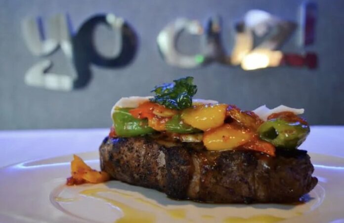 A juicy steak topped with yellow, red, and green peppers at Martorano's Prime.