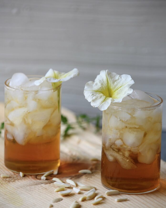 White flowers adorn two glasses of Italian Almond Cream Soda Cocktails.