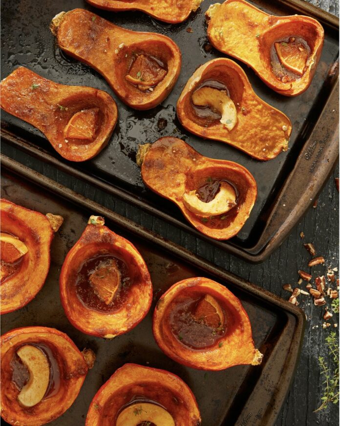 Roasted+Squash+With+Orange+And+Spices+ABLE+Magazine A variety of roasted squash on a baking sheet filled with orange slices and spices.
