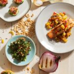 Baked salmon topped with pineapple mango salsa sits on a white dishes.