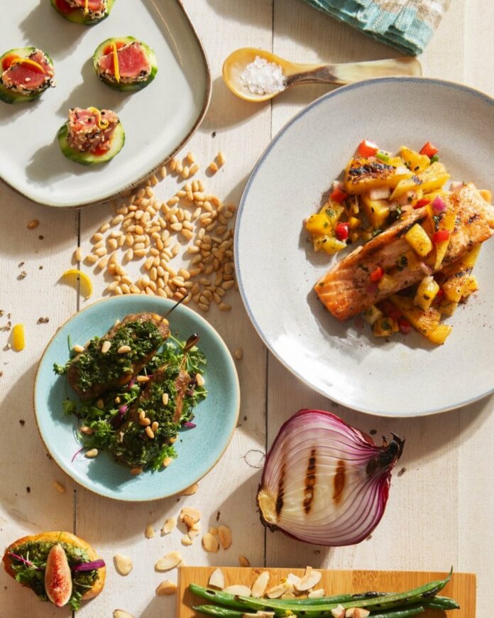 Baked salmon topped with pineapple mango salsa sits on a white dishes.