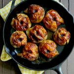 eight braised apples sit in a cast iron pan. braised apples recipe