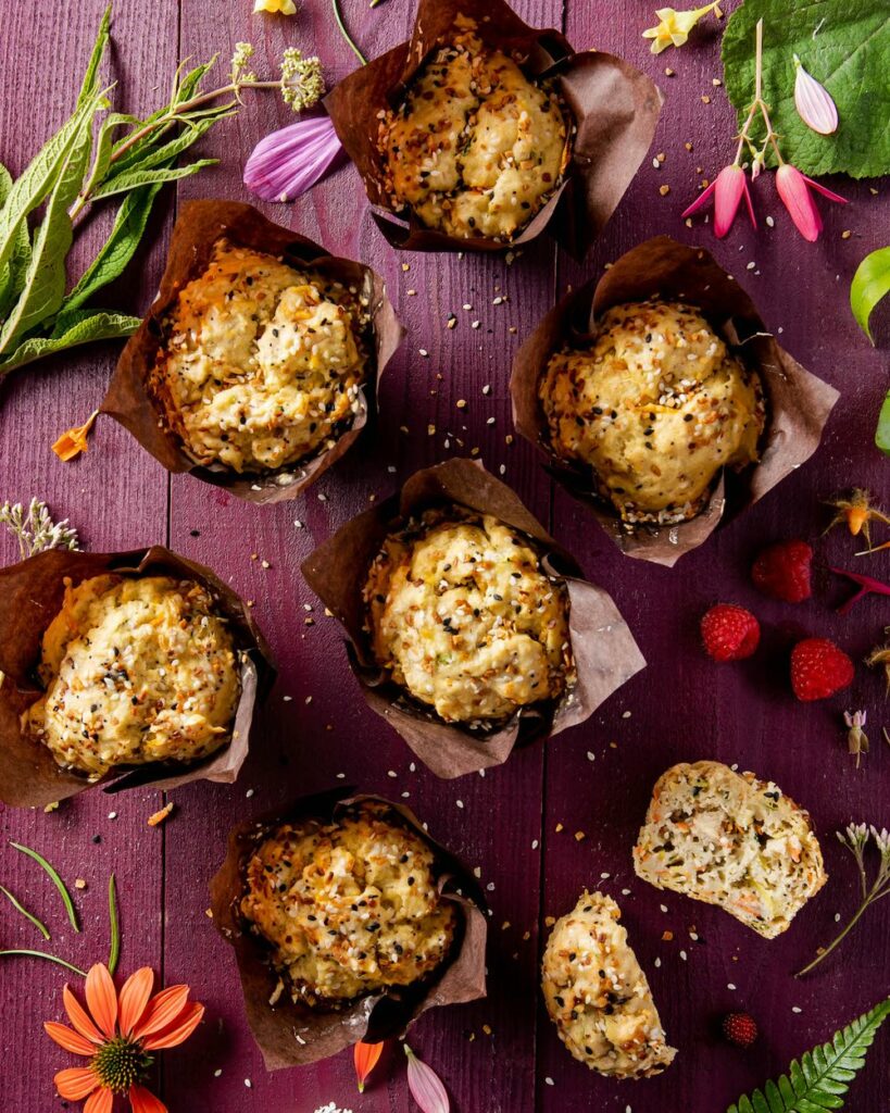 an aerial view of six veggie muffins against a purple table.