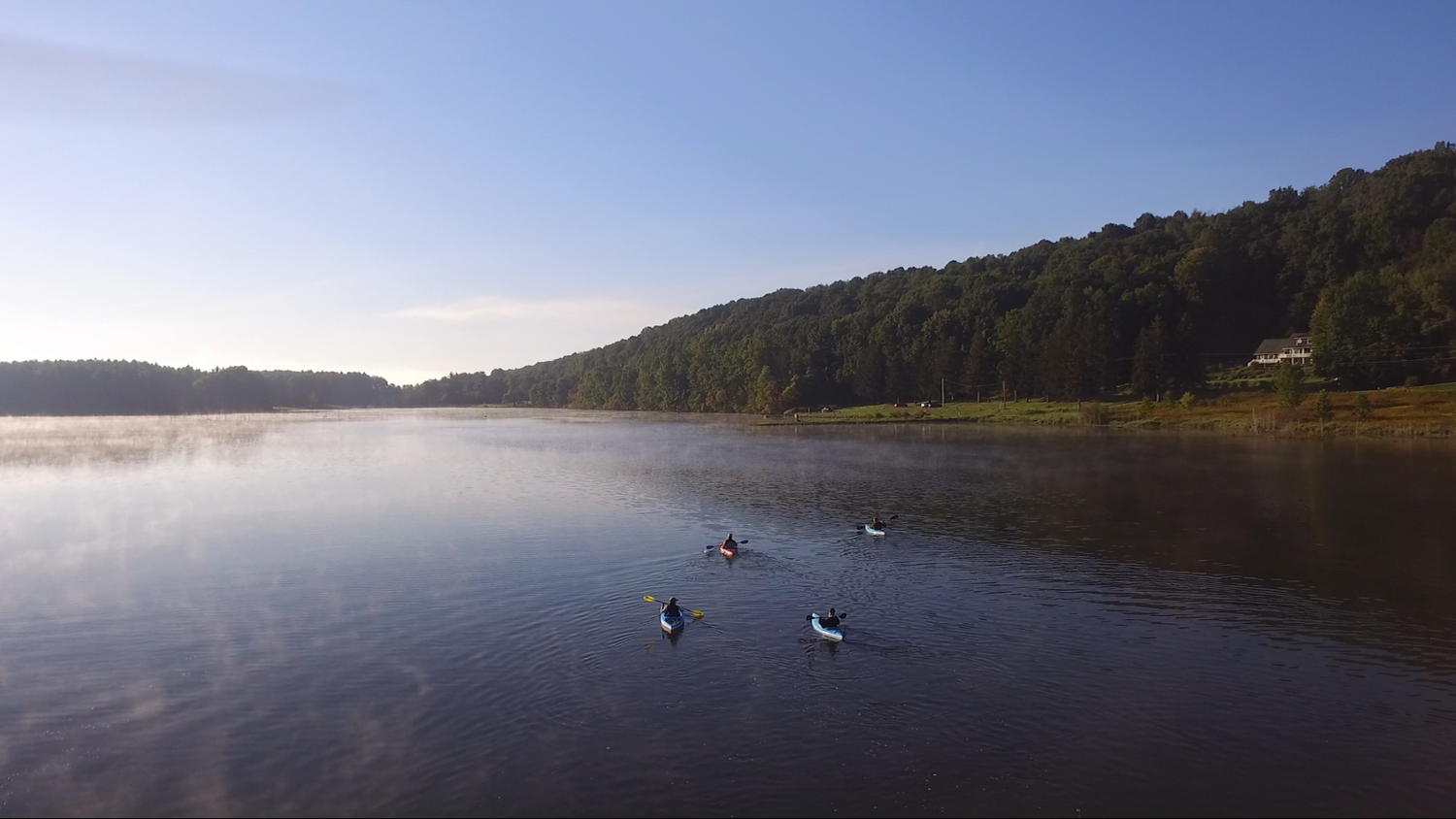 Four people in kayaks sit on a blue river in Crawford Country.