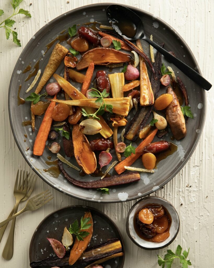 Roasted root vegetables served in a large grey bowl with a dried fruit sauce.
