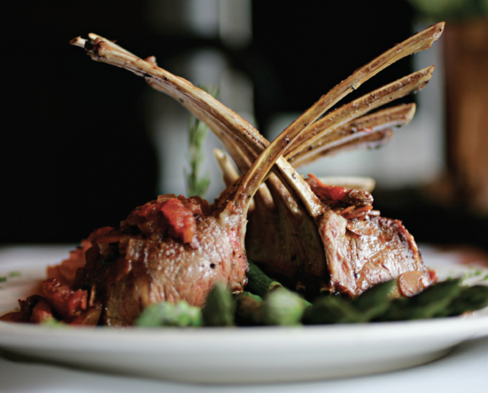Rack of lamb sits on a white plate.