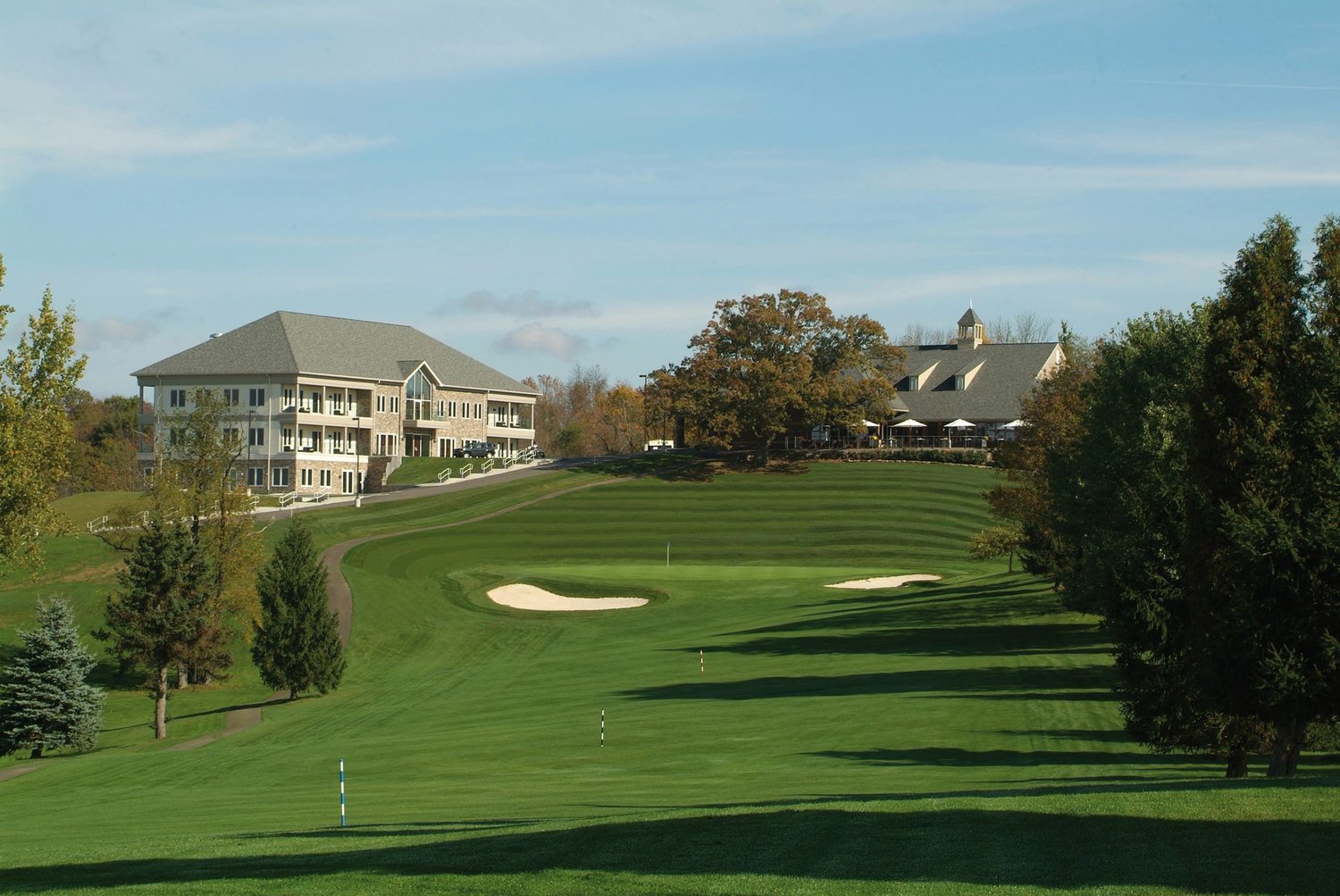 An expansive golf field with two sand pits sits in front of two modern looking buildlings