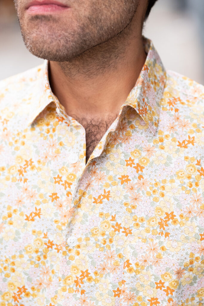 A photo close-up of a man wearing a floral Vestis buttodown shirt. 