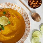 Allergen-free Golden Soup in a plate; a spoon, pieces of lemon, and chickpeas on the side.