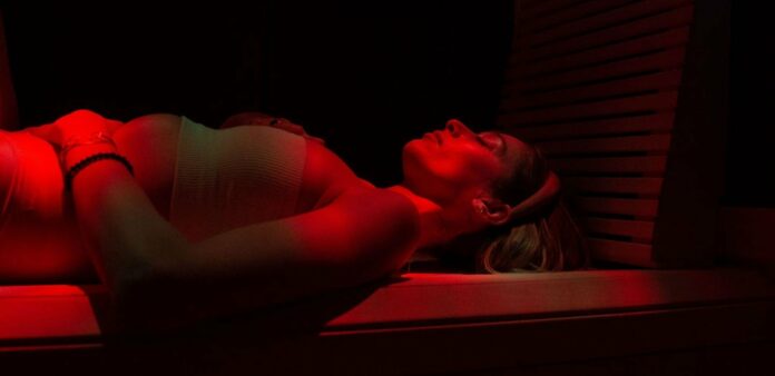 An image of a woman lying on her back in an infrared therapy sauna.