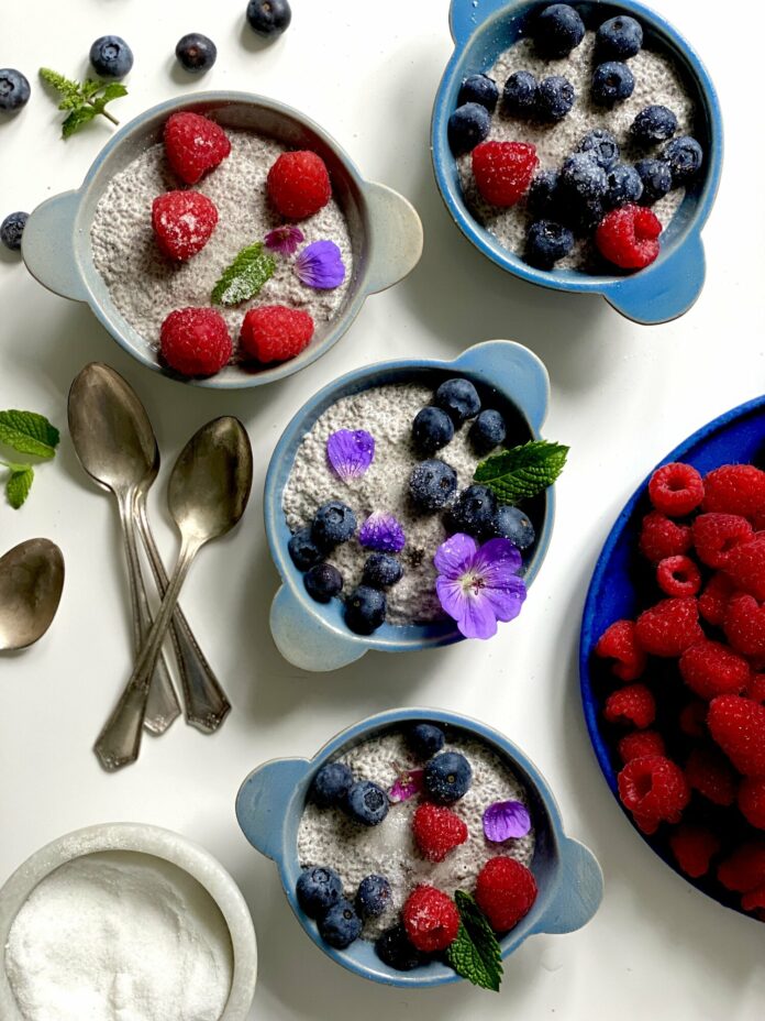 Chia seed pudding served in four bowls with three steel spoons on the side