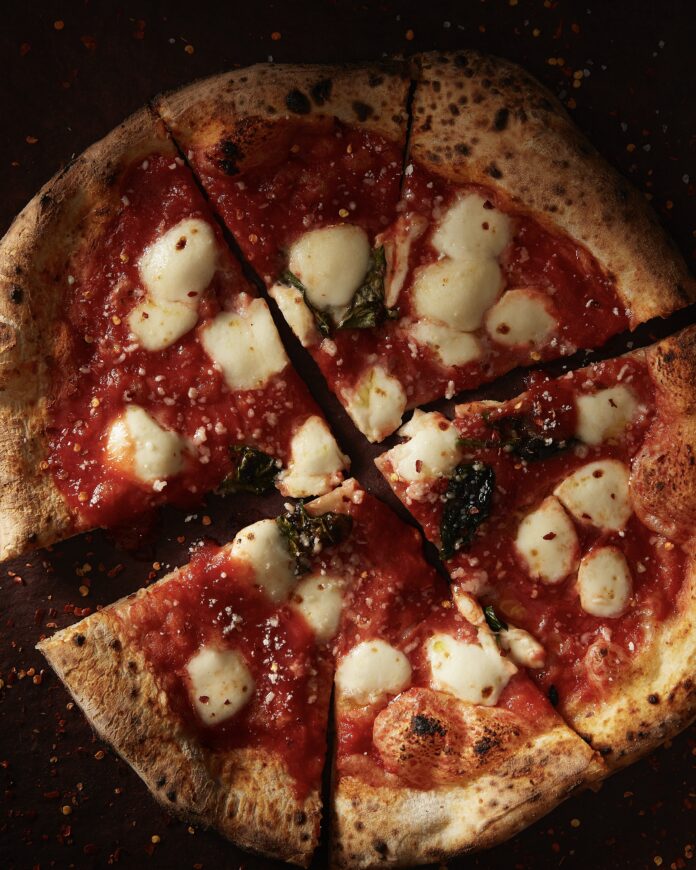 a sliced round pizza with red sauce and mozzarella balls