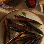 Honey and Ghee Roasted Carrots served on a ceramic plate with a sauce on the side