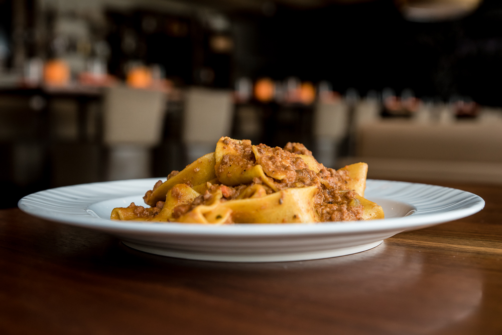 a white plate of pasta on a brown table