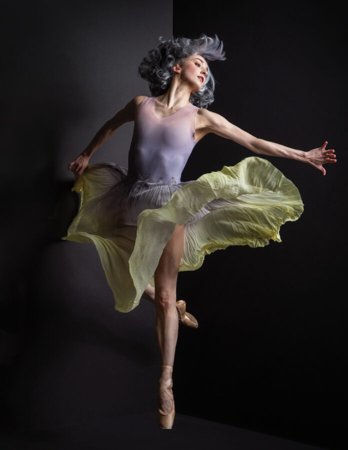 Pittsburgh Ballet Theatre Light in the Dark — a women in a light purple tank and flowly green skirt jumps in the air