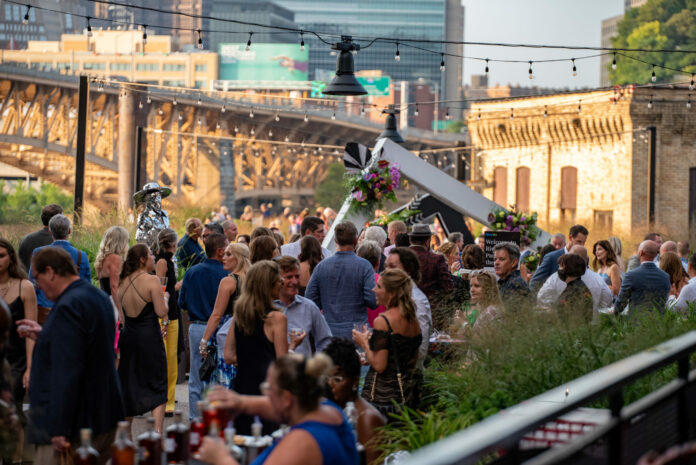 An image of a crowd of people mingling at a fundraiser. The city of Pittsburgh is in the background.