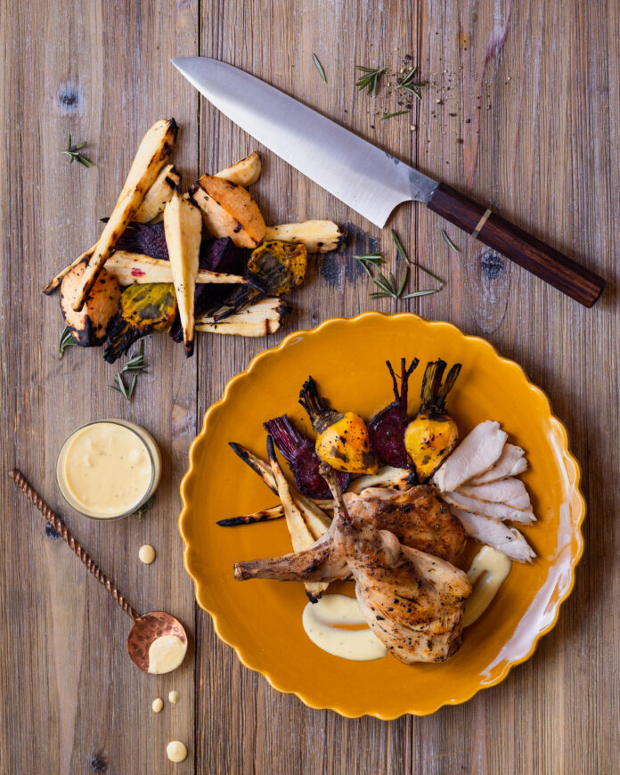 A duck breast with veggies on an orange plate sits in the right side of the frame, a knife is angled in the top right, and veggies sit to the left. Secrets of A Summer Sunday in the South of France