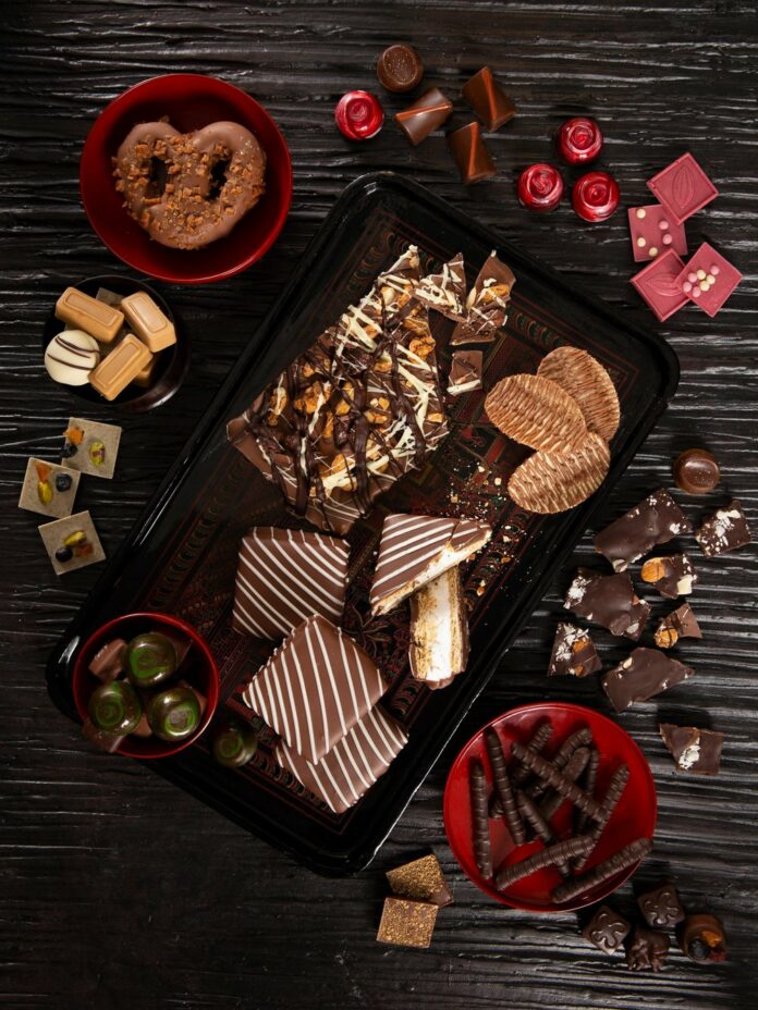 Valentine's Day Sweet Treats: Clockwise from top left: Sinful Sweets’ chocolate-covered pretzel dusted with toffee crumbs. Tabbara Chocolate’s stylish bonbons. Lux Artisan Chocolates’ macadamia nut, almond, and coconut bar. Sarris Candies’ chocolate-covered pretzel sticks. More candies from Tabbara Chocolates. On the tray, from top: Toffee Taboo from All in Good Taste Productions. Chocolate-striped potato chips from Sarris Candies. Chocolate-covered s’mores from The Milkshake Factory.