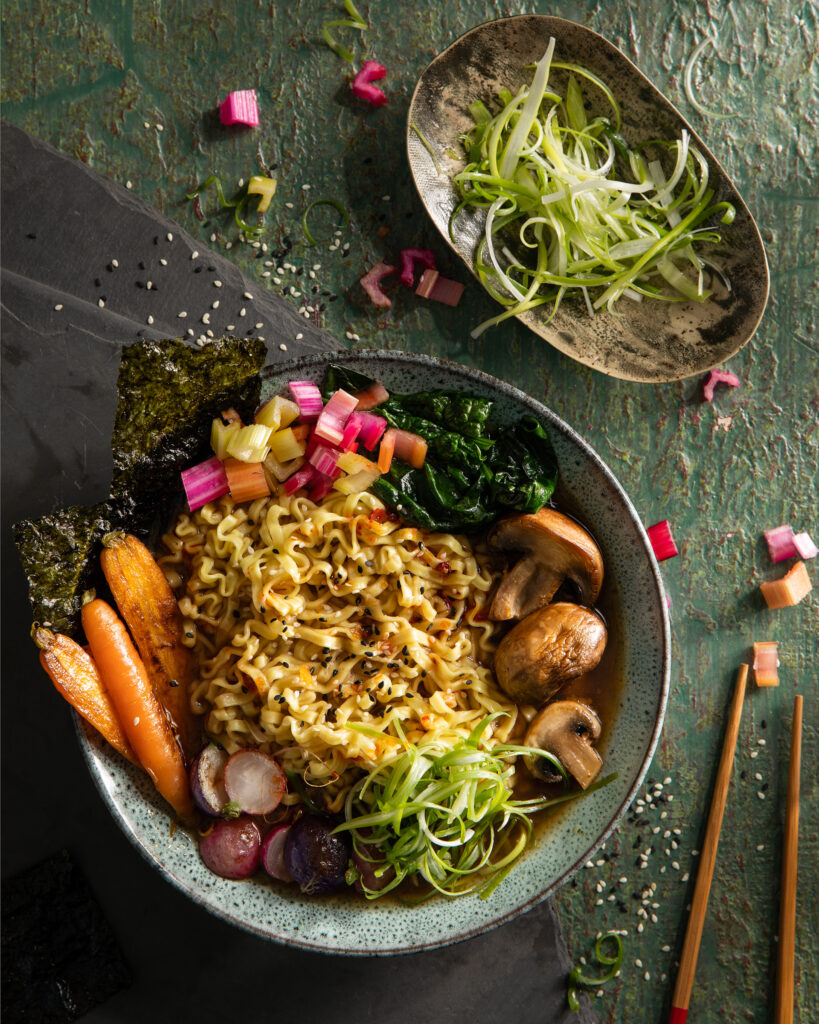 A flay-lay image of vegetarian ramen bowls with various vegetables and garnishes. Vegetarian meal.