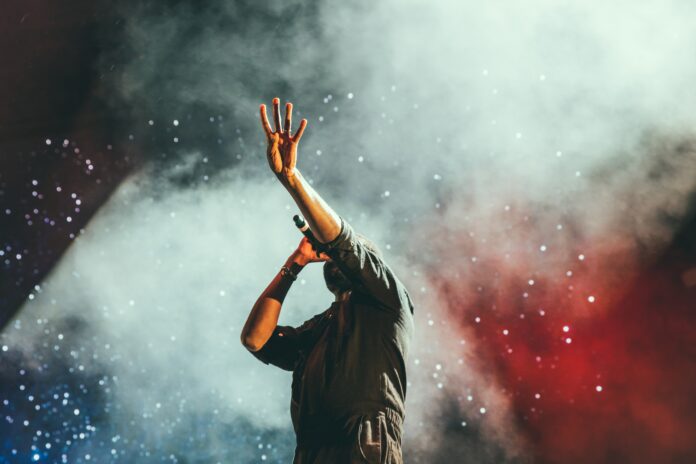 a performer on stage sings in front of a full crowd. Pittsburgh music venue