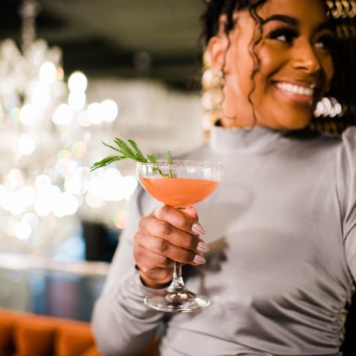 an attractive woman holding a cocktail in a restaurant