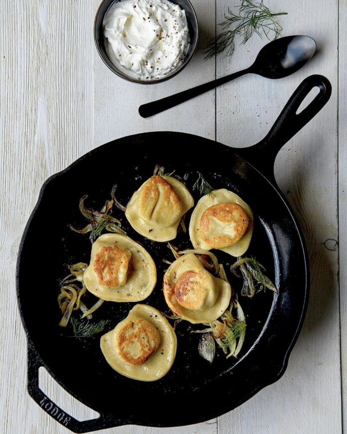 five pierogis in a black iron skillet on a white table