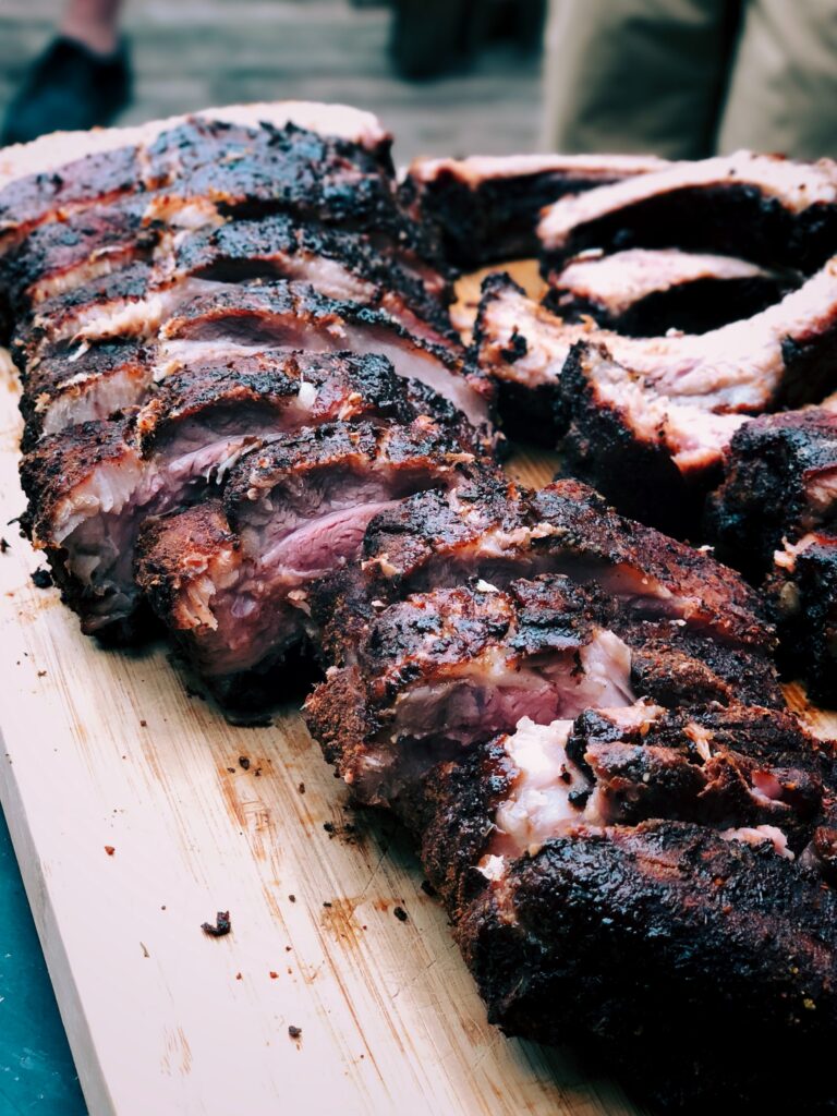 A rack of Babyback Ribs spread out on a wooden board.