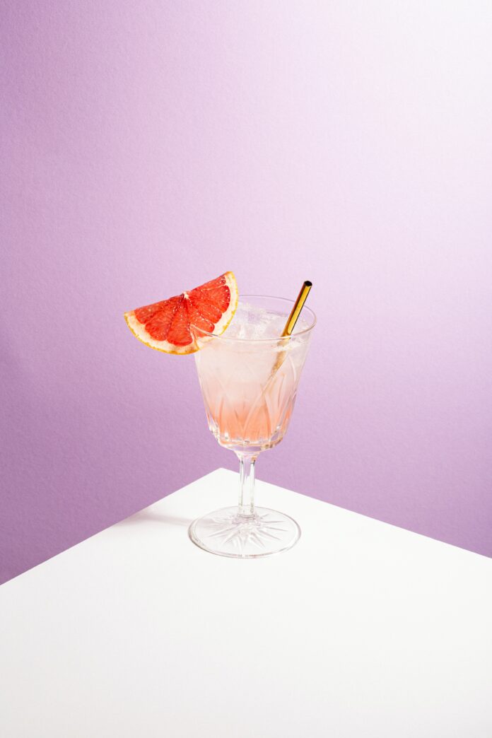 A grapefruit drink with a slice of grapefruit and a reusable straw
