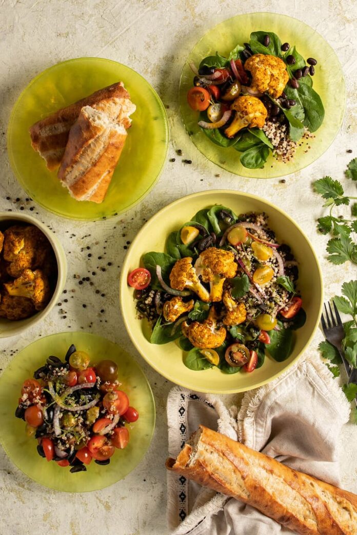 Colorful cauliflower salad with quinoa, fresh vegetables, olives, and crusty bread.