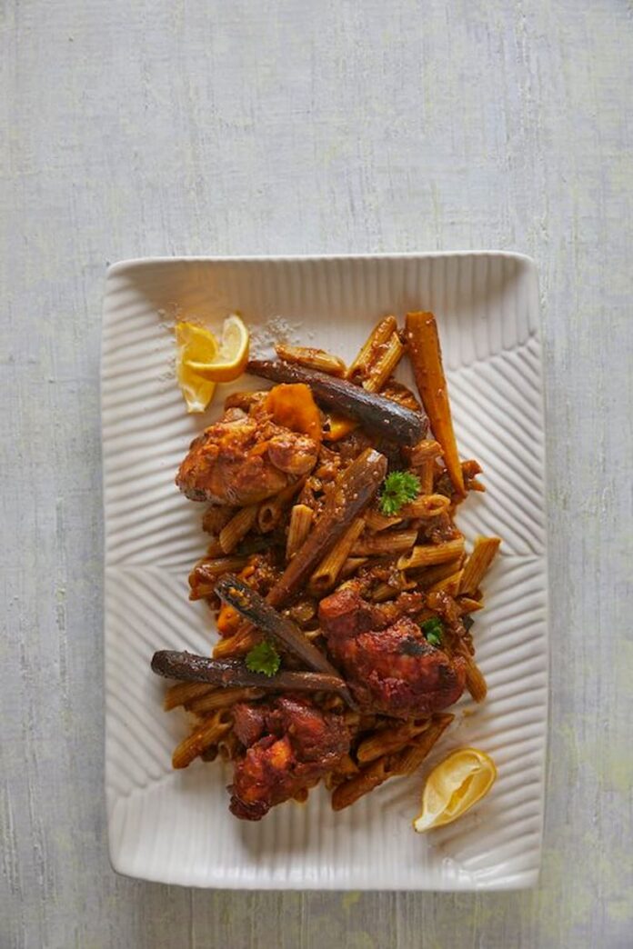 A plate of chicken harissa gluten-free pasta on a white background