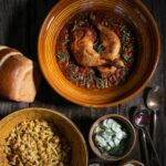 Chicken Paprikash served in a bowl along with bread and side dishes