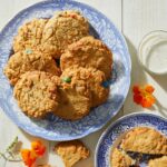 Kitchen Sink Cookies served on two stylish, ceramic plates with flowers on the side