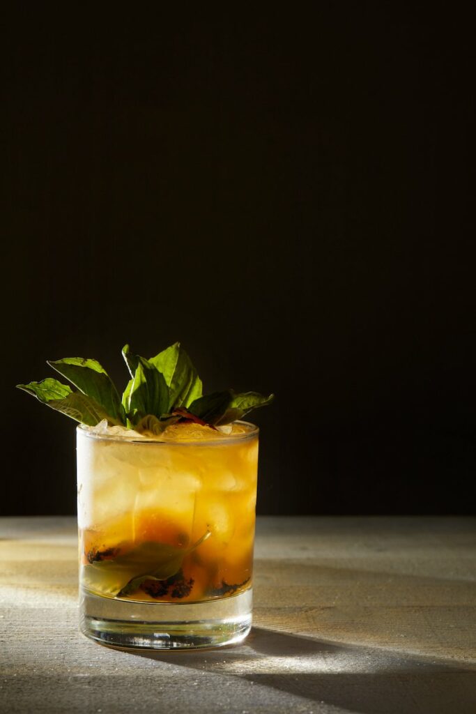 Deliciously refreshing grilled peach smash cocktail with fresh mint and a hint of citrus, served in a stylish glass.