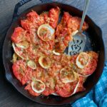 Summer Scalloped Tomatoes in a pan with a large spoon inside and a cloth on the side