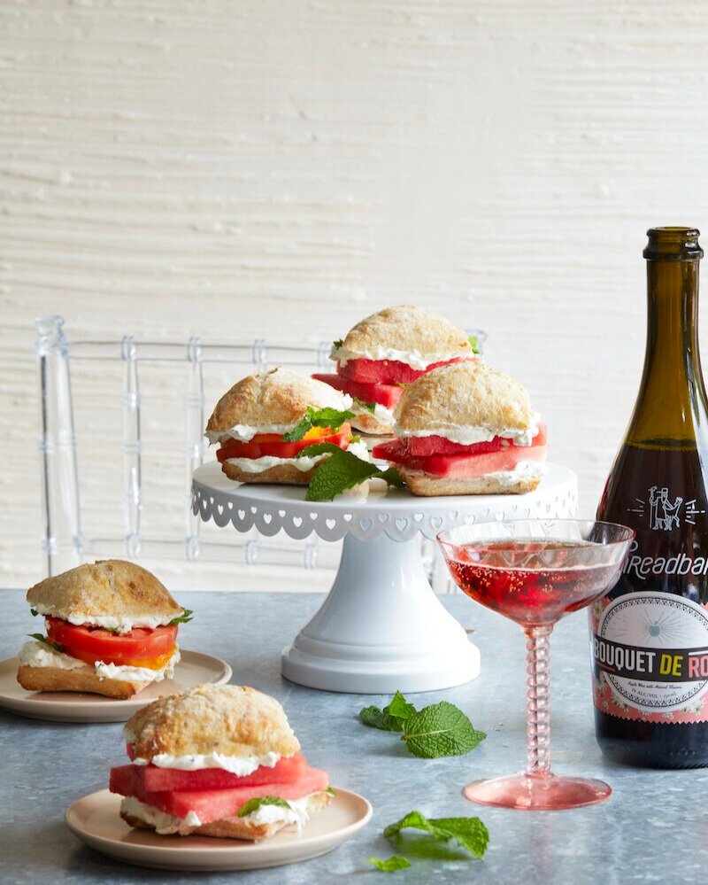 Three Watermelon Sandwiches served on a heightened plate. Two sandwiches served on two smaller plates on the side.