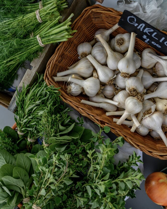 fresh green herbs and a basket filled with fresh garlic