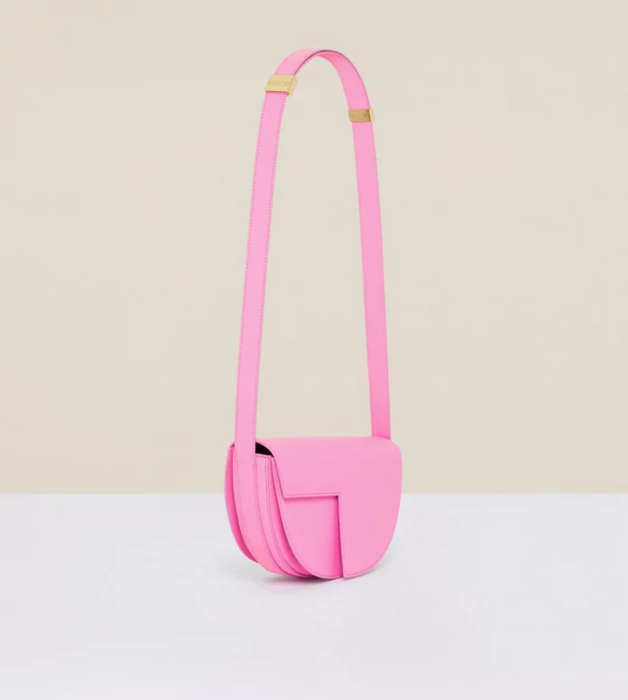 A bright pink shoulder bag with a long strap