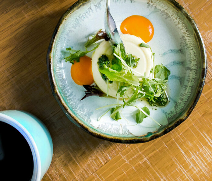 An aerial shot of a creamy bowl of corn flan, egg yolks and thyme sit on top. Corn Flan Recipe
