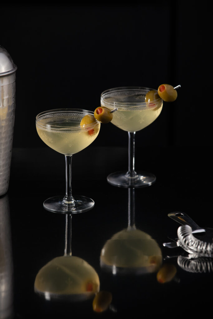 Two dirty martini cocktails sit in martini glasses